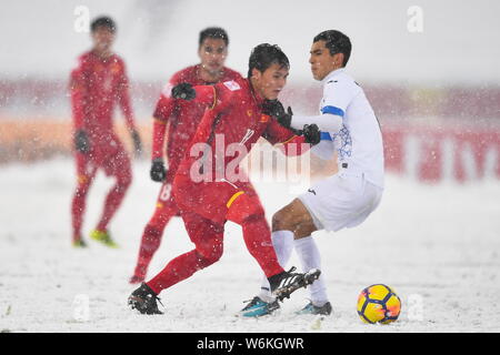 Nguyen Quang Hai, gauche, du Vietnam frappe la balle pour faire une passe contre un joueur de l'Ouzbékistan dans leur dernier match de lutte pour la championne au cours de Banque D'Images