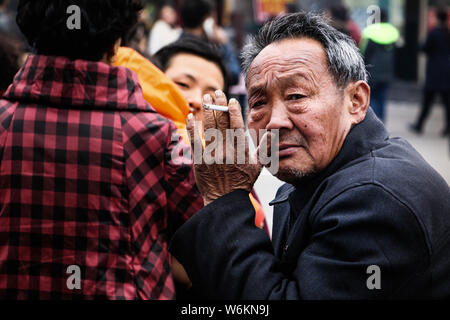 --FILE--Un homme âgé fume une cigarette qu'il attend que son train en gare de l'est de la Chine dans la province de Shandong, 12 février 2016. Un repo Banque D'Images