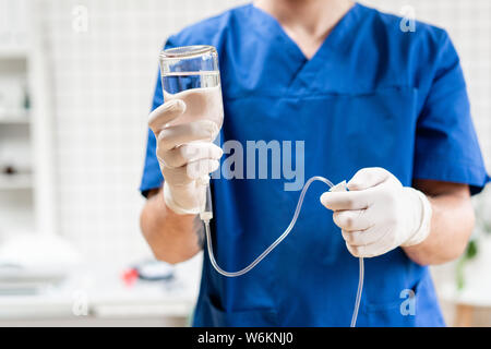 Médecin en uniforme bleu goutte holding iv et pompe à perfusion. Concept d'urgence un traitement médical.. Fluide intraveineux pour patient gravement dans le Banque D'Images