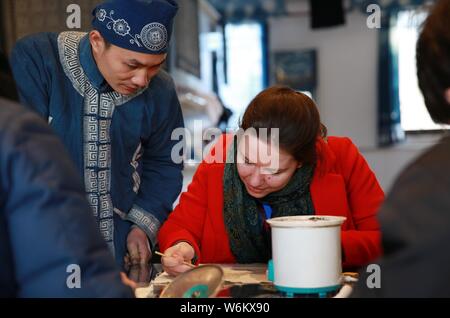 Un étudiant étranger essaie les Miao batik ethnique avec l'aide d'un artisan dans le comté de Danzhai, Qiandongnan Préfecture autonome Miao et Dong, au sud Banque D'Images