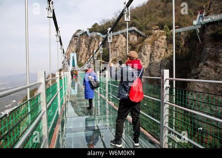 Des touristes posent pour des photos sur le pont en verre appelé "Dragon Volant dans le ciel' dans Marenqifeng zone touristique dans la ville de Wuhu, à l'est la province de l'Anhui, Chine Banque D'Images