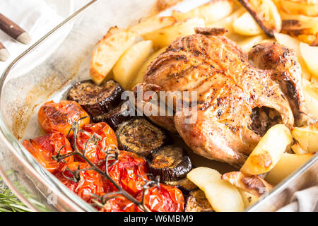 Poulet entier cuit au four avec des pommes de terre, l'aubergine et les tomates cerises. repas sain. Banque D'Images