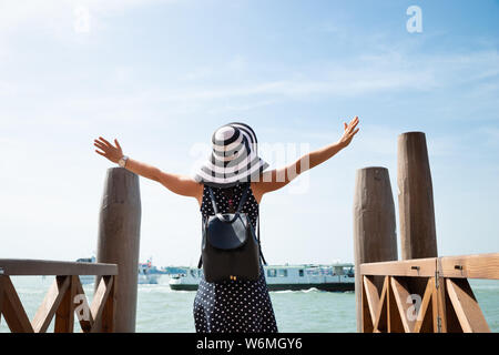 Vue arrière d'une femme debout sur les mains Outstretching Pier profiter de vacances à Venise Banque D'Images