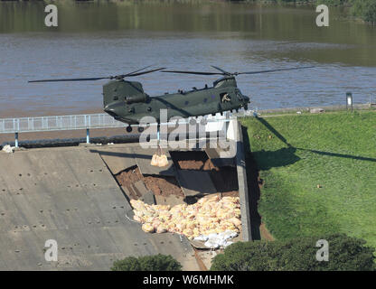 Un hélicoptère Chinook de la RAF dans les mouches de sable pour aider à réparer le barrage réservoir à Toddbrook près du village de Whaley Bridge dans le Derbyshire, après qu'il a été endommagé par de fortes pluies. Banque D'Images