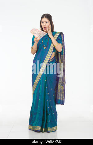 South Indian woman surprisingly looking at banknotes Stock Photo