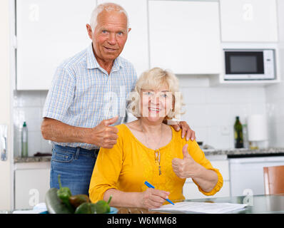 Portrait of mature couple à table de cuisine du remplissage des documents Banque D'Images