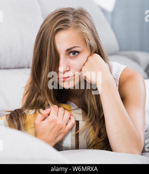 Portrait de sad young woman lying on sofa coussin Banque D'Images