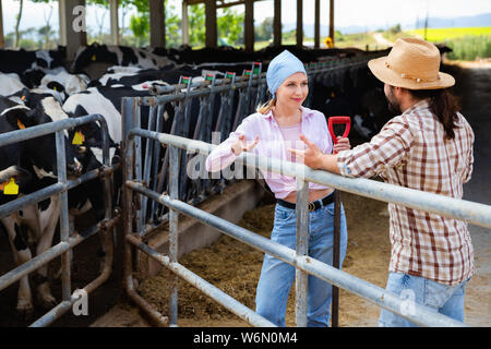 Young happy happy smiling farm family standing près de l'escrime en étable, communication lors d'interruption de travail Banque D'Images