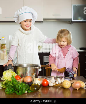 Deux mignonnes petites sœurs avec pot smiling at home cuisine Banque D'Images