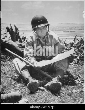 Avec sa prise de Naha capital comme arrière-plan, le général de Marine Lemuel Shepherd, général commandant de la 6e Division de marines, se détend sur une crête Okinawan assez longtemps pour consulter une carte du terrain., ca. 06/1945 Banque D'Images