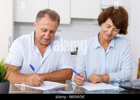 Portrait of mature couple positif au remplissage des documents table de cuisine Banque D'Images