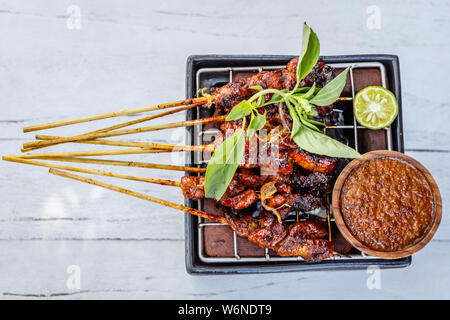 Sate sate ayam (poulet, viande grillée sur des brochettes de bambou), plat traditionnel Indonésien, servi avec le sambal kacang, sauce aux cacahuètes. Bali, Indonésie. Banque D'Images