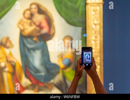 Dresde, Allemagne. 09Th Aug 2019. Dans l'exposition 'Glanzlichter der Gemäldegalerie Alte Meister' dans Semperbau, un visiteur photographies le travail "istine Madone" par Raphaël. L'exposition dure du 2 août au 3 novembre 2019 et offre un aperçu de la 3800 œuvres de la collection. Credit : Matthias Rietschel/dpa-Zentralbild/ZB/dpa/Alamy Live News Banque D'Images