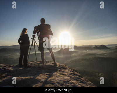 Couple de touristes avec trépieds et caméras permettent de prendre des photos à l'arrière-plan de belles collines et le ciel. Les jeunes dans une randonnée en montagne. La liberté et trav Banque D'Images