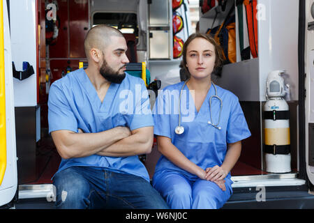 Portrait de deux ambulanciers positif assis en voiture ambulance Banque D'Images