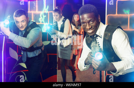 Groupe de joyeux collègues holding smiling positive pistolets laser laser tag jeu jeu Banque D'Images