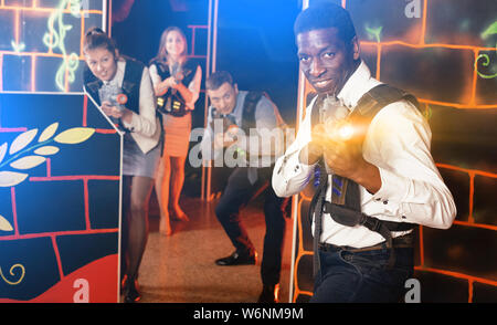 Groupe de collègues souriants positive holding pistolets laser laser tag jeu jeu Banque D'Images