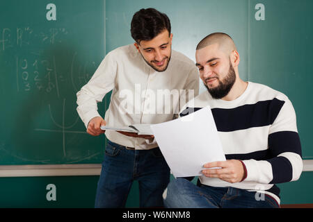Portrait de deux jeunes hommes discutent de leur projet étudiant at desk in classroom Banque D'Images