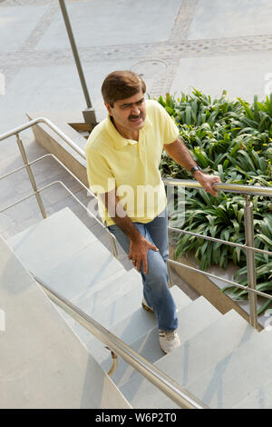 Homme qui a du mal à monter les escaliers Banque D'Images