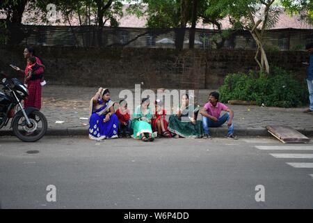 Famille indienne, assis sur le trottoir en attendant le New Years Day Parade d'aller par de fort Kochi, Kerala, Inde. Banque D'Images