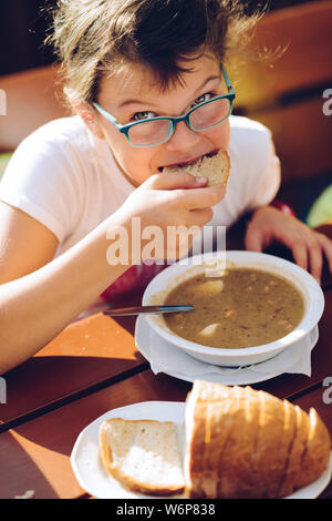 Petite fille dans les verres de manger de la soupe et du pain Banque D'Images