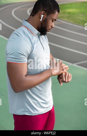 L'homme athlétique concentré à la remise en forme à son tracker Banque D'Images