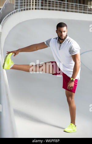 Beau jeune homme sportif pensif faisant d'entraînement de jambe Banque D'Images