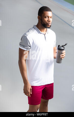 Jeune homme tenant une bouteille d'eau sport en plastique Banque D'Images