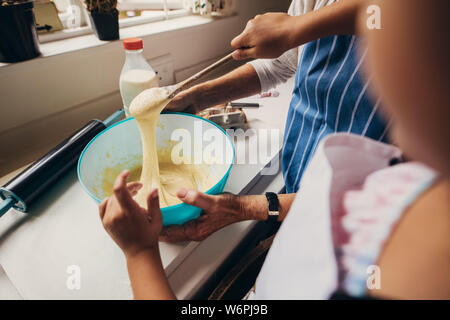 Close up de mains de deux personnes faire la pâte à gâteau. Les femmes mixer dans un bol en cuisine. Banque D'Images