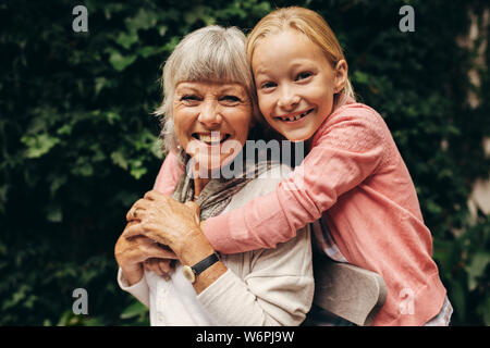 Close up of a smiling kid holding sa grand-mère par derrière. Heureux grand-mère et enfant dans un parc qui se tiennent. Banque D'Images