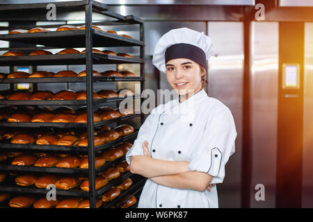 Portrait d'une jeune fille sur Baker l'arrière-plan d'un four industriel avec des pâtisseries dans une boulangerie. Banque D'Images