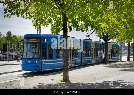 Storstockholms Lokaltrafik SL ou tram bleu rétroéclairé et des chemins de fer suédois avec des arbres à feuillage vert. (Östermalmstorg Djurgarden). Stockholm, Suède. Banque D'Images