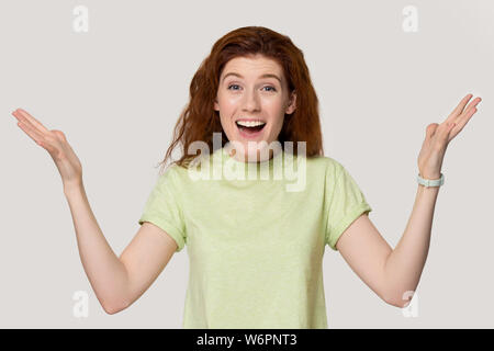 Femme rousse heureux excité soulever palms posant sur fond gris Banque D'Images