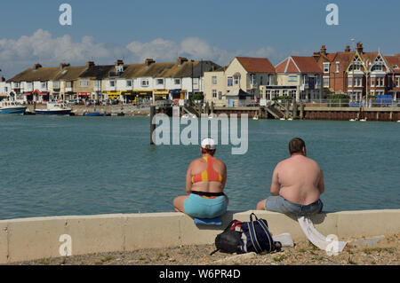 Un excès de couple assis sur le bord de l'eau. Littlehampton, West Sussex, England, UK Banque D'Images