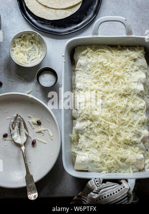 Les enchiladas en devenir. Les tortillas sur la plaque remplie de poulet au fromage et haricots noirs Banque D'Images