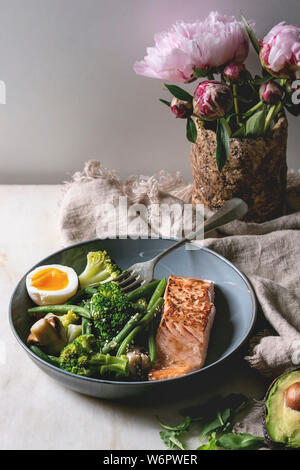 Bas carb régime cétogène dîner saumon grillé, avocat, brocoli, haricot vert et doux oeuf dur dans un bol en céramique servi avec des olives et des noix, bouquet Banque D'Images