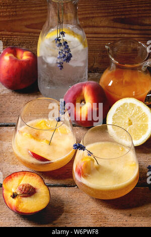 Peach Bellini cocktail froid limonade ou avec des fleurs de lavande servi dans deux verres avec cruche de jus de citron et pesh le soda sur rustique en t Banque D'Images