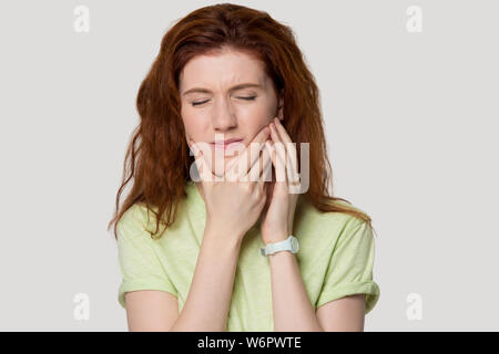 Head shot studio portrait femme rousse ayant mal de dent Banque D'Images