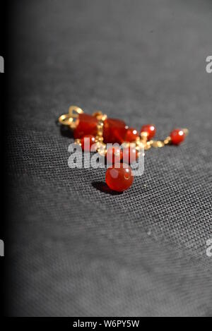 Bijoux en or rouge sur la case close up très belle sur fond gris bracelet ou un collier brillant orange crystal boucles d Banque D'Images