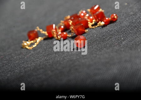 Bijoux en or rouge sur la case close up très belle sur fond gris bracelet ou un collier brillant orange crystal boucles d Banque D'Images