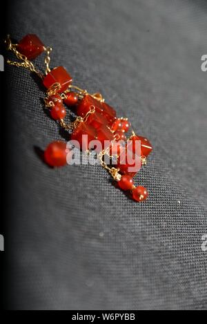 Bijoux en or rouge sur la case close up très belle sur fond gris bracelet ou un collier brillant orange crystal boucles d Banque D'Images