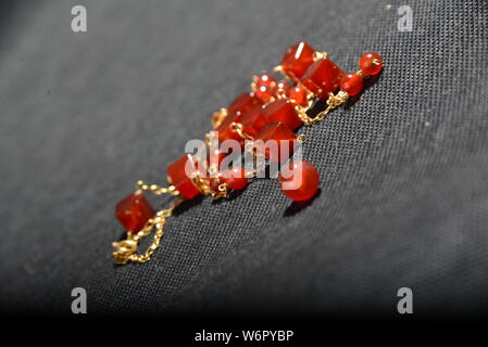 Bijoux en or rouge sur la case close up très belle sur fond gris bracelet ou un collier brillant orange crystal boucles d Banque D'Images