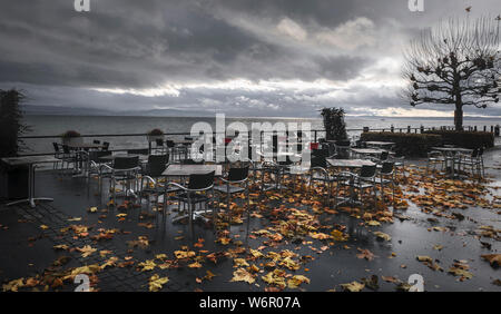 En plein air de l'automne paysage avec tables et chaises vides humides, sur la terrasse d'un restaurant sur les rives du lac de Constance, à Friedrichshafen, Allemagne. Banque D'Images
