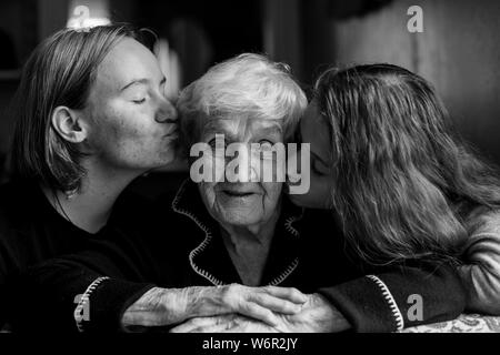 Petite-fille de deux filles s'embrasser les joues de sa vieille grand-mère. Photo en noir et blanc. Banque D'Images