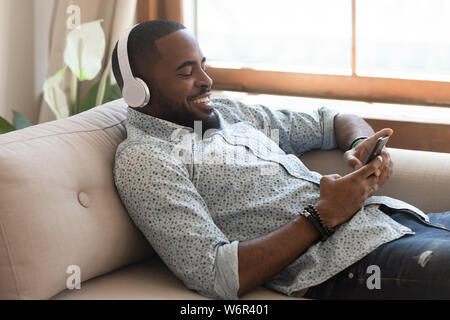 Ambiance african man wearing headphones listening music mobile sur smartphone Banque D'Images