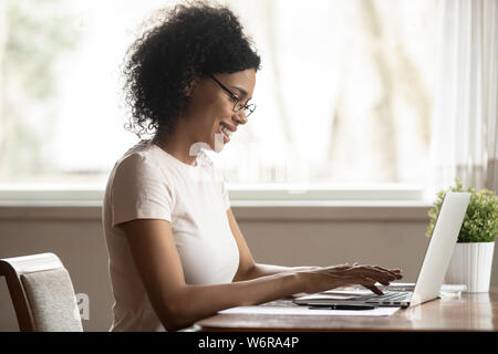 African woman sitting at table travailler sur ordinateur à la maison Banque D'Images