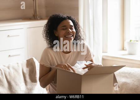 Femme africaine excité déballage du carton fort parcelle se sent heureux Banque D'Images