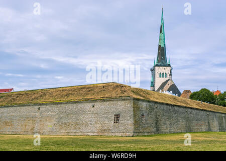 Flèche de l'Église Saint-olaf contre le ciel bleu derrière la muraille de la ville de la vieille ville de Tallinn. Banque D'Images