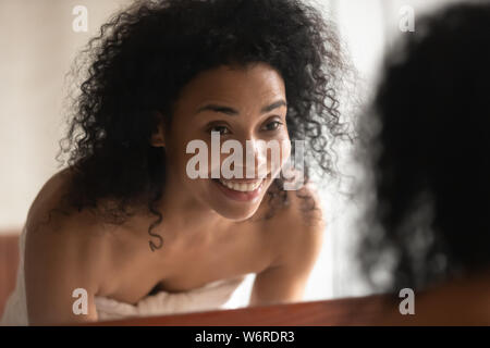 Femme africaine lave son visage dans la salle de bains miroir à Banque D'Images