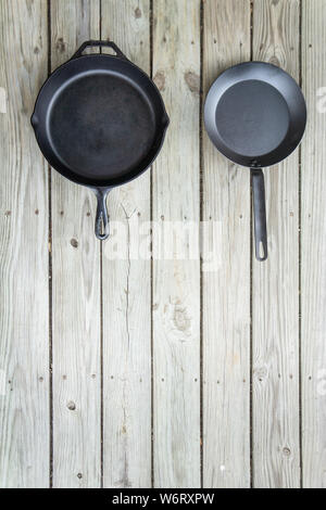 Cuisine traditionnelle vs nouvelle bataille - fontes par rapport à l'acier au carbone ou en téflon. Fond de bois. Ustensile de cuisine plus saine des options. R texte vide vide Banque D'Images